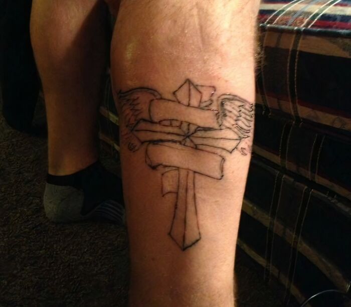 Failed tattoo design with wings and ribbons on a person's calf.