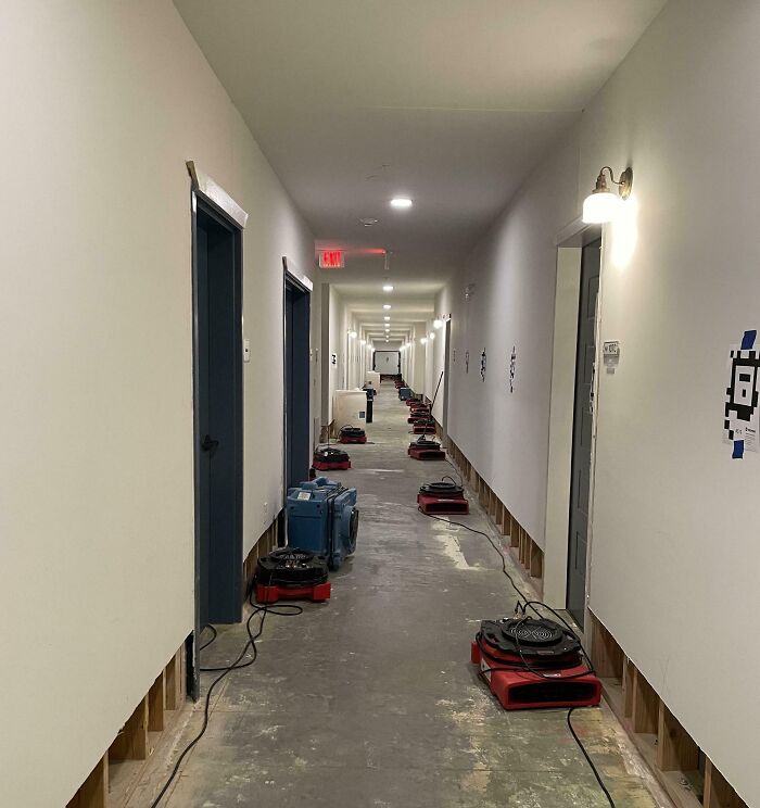 Hallway under repair with industrial fans, possibly due to water damage, illustrating a Christmas season accident.