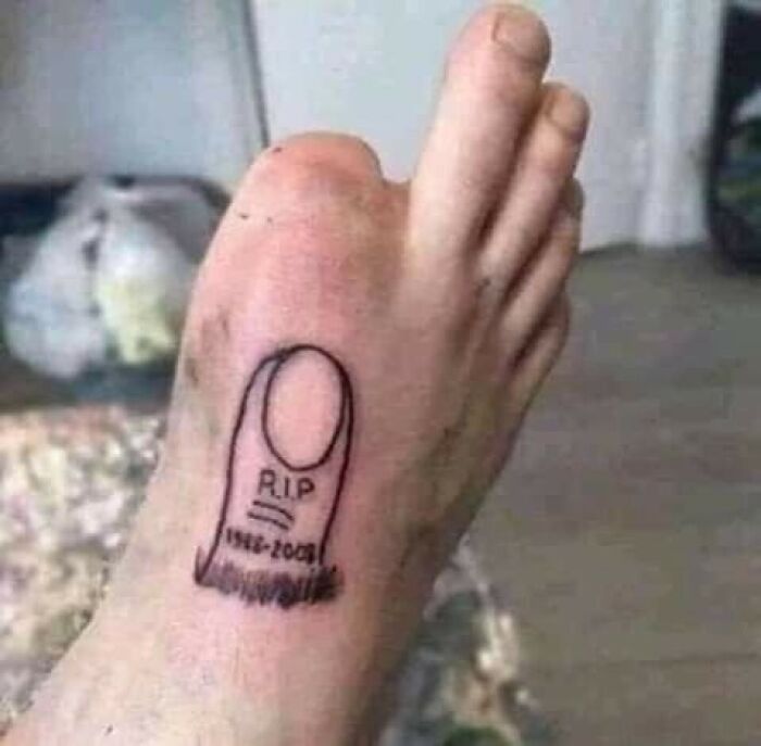 Cursed image: toe with gravestone tattoo reading "R.I.P. 1992-2023," suggesting humor or dark creativity.