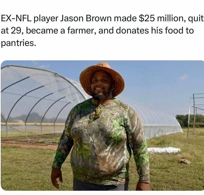 Man in a camo shirt and straw hat stands smiling on a farm next to a greenhouse, illustrating wholesome kindness.