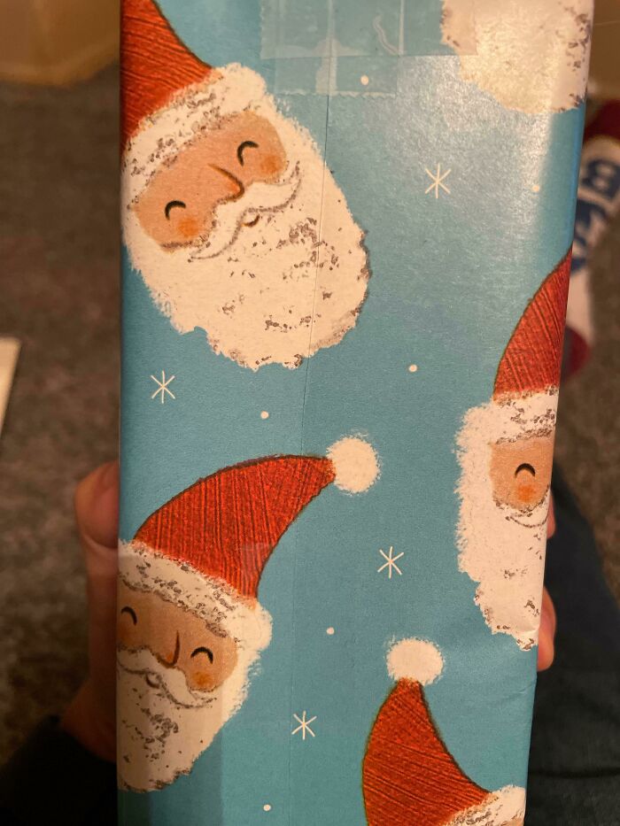 Gift wrapped in Santa paper with perfect fit alignment on a blue background.