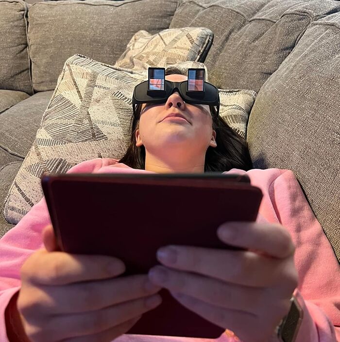 Person on couch using reflective glasses, holding a tablet; a quirky gift idea for antisocial people.