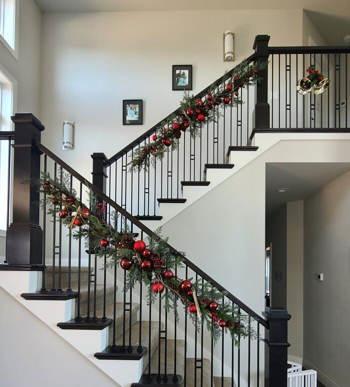 Christmas decorating ideas with a staircase adorned with garland and red ornaments.