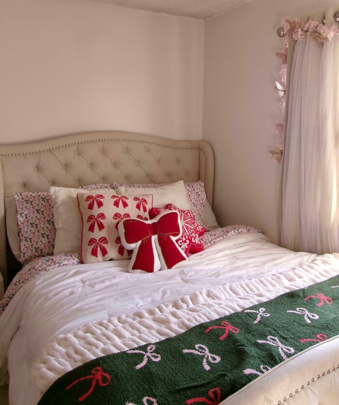 Cozy bedroom with festive bedding, featuring red and green Christmas decorations and holiday-themed pillows.