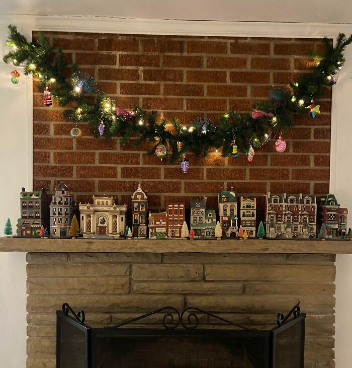 Christmas-decorating-ideas with a garland on a mantle and a charming miniature village below.