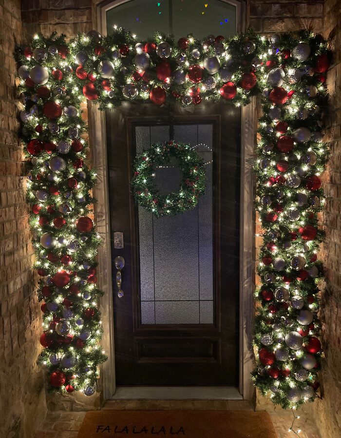 Festive doorway with Christmas decorations, including wreath, garland, and lights, showcasing holiday decorating ideas.