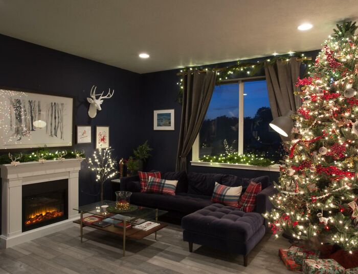 Cozy living room with Christmas-decorating-ideas, featuring a lit tree, garlands, and festive pillows by the fireplace.