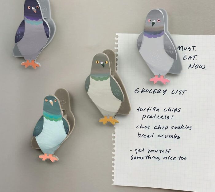 Pigeon magnets holding a grocery list with quirky items on a fridge.