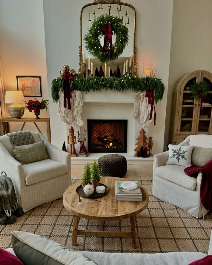 Cozy living room with festive Christmas decorating ideas, featuring a wreath, stockings, and candles on the mantel.