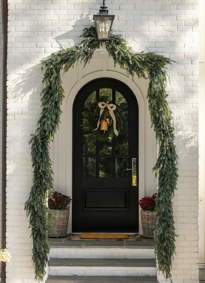 Festive door with evergreen garland and wreath, showcasing elegant Christmas decorating ideas.