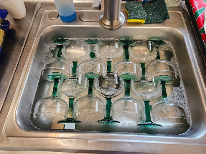 Wine glasses perfectly arranged in a kitchen sink, creating a satisfying pattern and perfect fit.