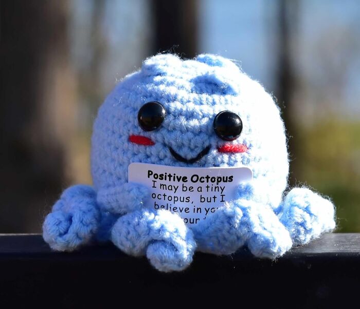 Crocheted octopus holding a card, perfect for antisocial gifts.