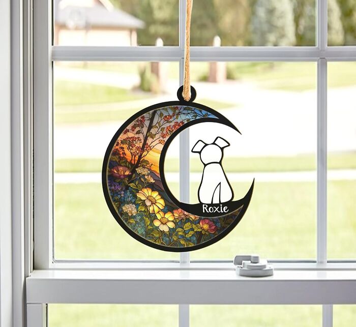 Holiday-themed pet decoration hanging on a window, featuring a floral and sunset design.