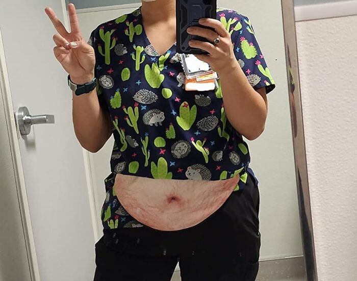 Person in cactus-themed scrub top holding up a phone with a funny belly apron, perfect for white elephant gifts.