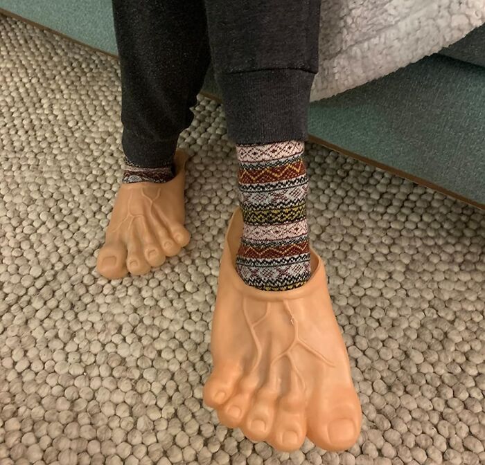 Giant foot slippers on a person wearing patterned socks, perfect for white elephant gifts.