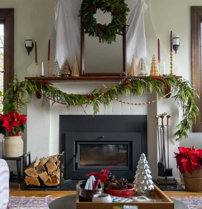 Cozy fireplace with Christmas-decorating-ideas, featuring garland, wreath, and festive candles on the mantel.