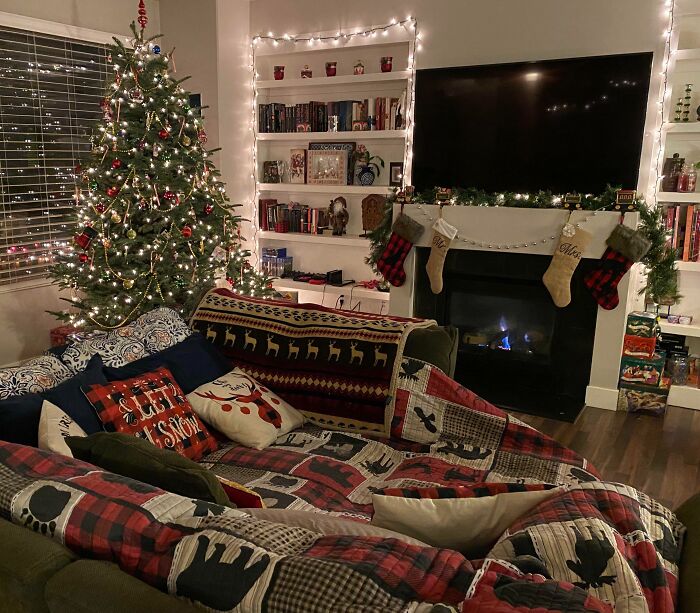 Cozy living room with a decorated Christmas tree, lit fireplace, and festive stockings hung on the mantel.