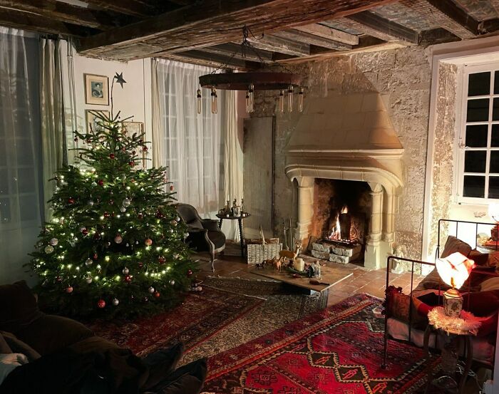 Cozy living room with a decorated Christmas tree, warm fireplace, and festive holiday ambiance.