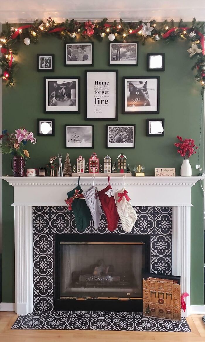 Fireplace with Christmas-decorating ideas: garland, stockings, and framed photos on a green wall.