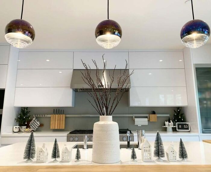 Modern kitchen with Christmas-decorating-ideas; featuring a white vase, mini trees, and ceramic houses on a countertop.