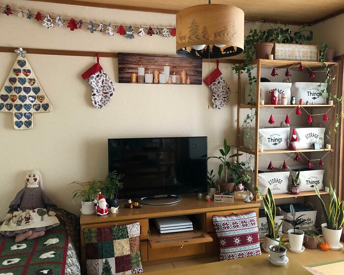 Cozy living room with festive Christmas-decorating ideas, featuring stockings, plants, and a TV stand adorned with holiday decor.