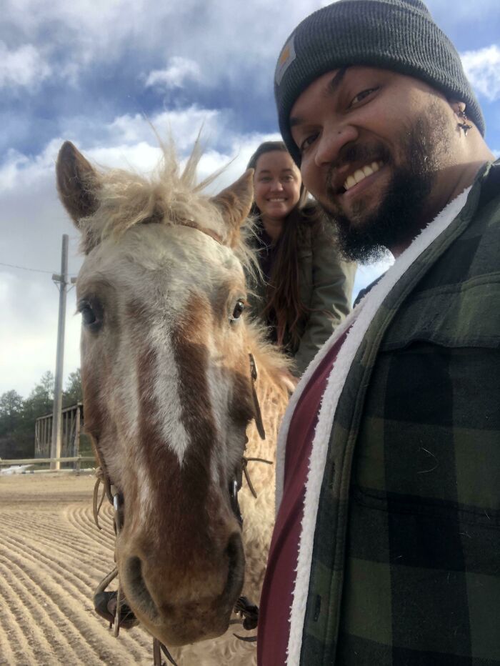 Smiling people with a horse outdoors, capturing a wholesome Christmas moment in the fresh air.