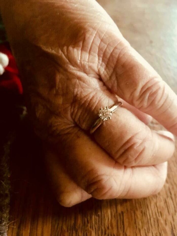 Elderly hand with a sparkling ring, capturing a wholesome Christmas moment on a wooden table.