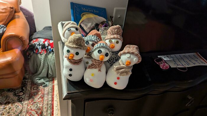 Seven snowmen with button eyes and scarves, arranged on a table, bringing a touch of Wholesome Christmas charm indoors.