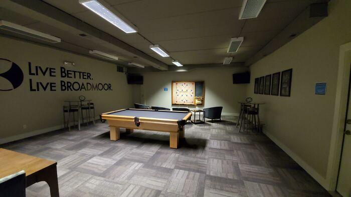 Pool table room with dim lighting and modern decor, resembling a video game setting.