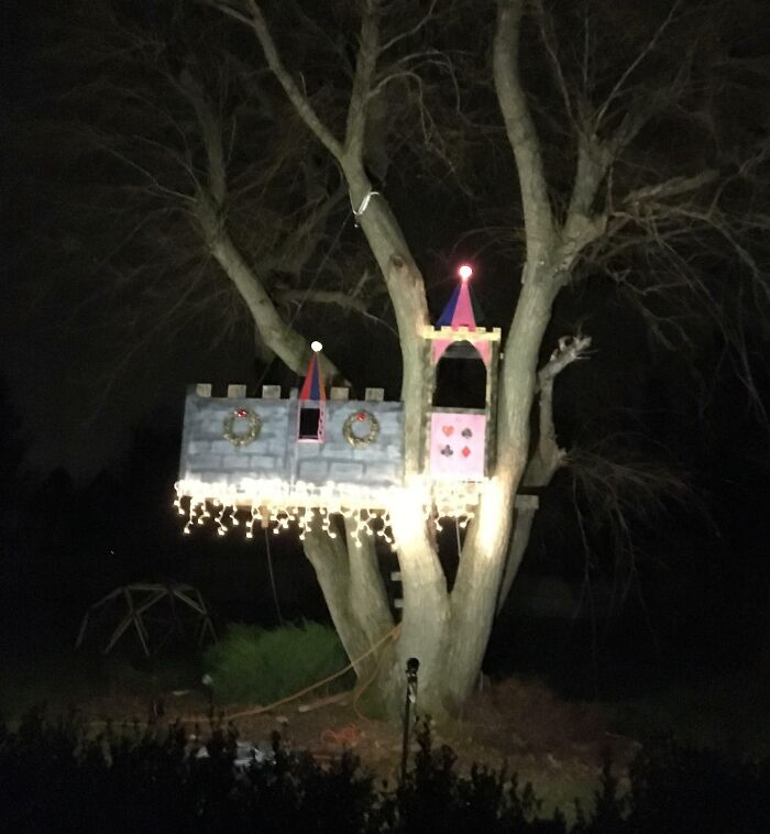 Treehouse decorated with Christmas lights and wreaths, creating a whimsical holiday scene.