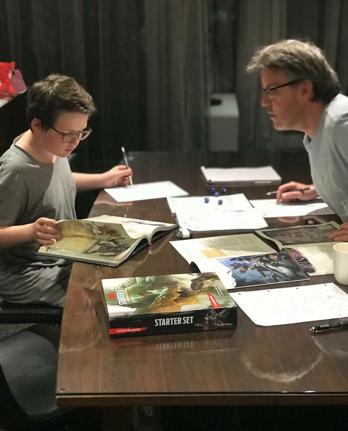 Father and son enjoying a game night with books and dice, creating a wholesome Christmas moment.