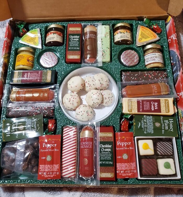 Subscription box with a variety of snacks including cheese, sausage, and cookies.