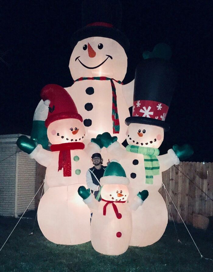 Inflatable snowmen family glowing in the dark, creating a wholesome Christmas display in a yard.