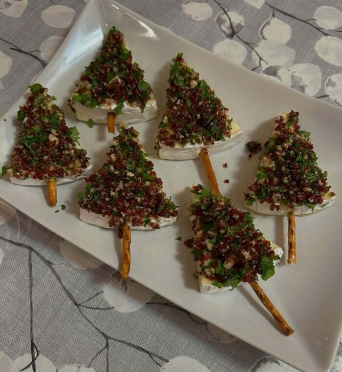 Christmas snack food ideas featuring cheese trees with pretzel sticks and herb toppings on a plate.