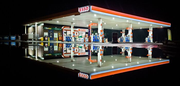 Gas station at night reflected perfectly on water, resembling elements from videogames.