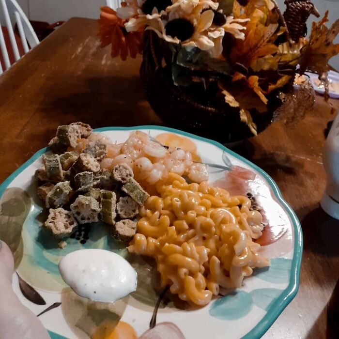 A plate of mac and cheese, shrimp, and fried okra looks like a bad render, with fall decorations in the background.