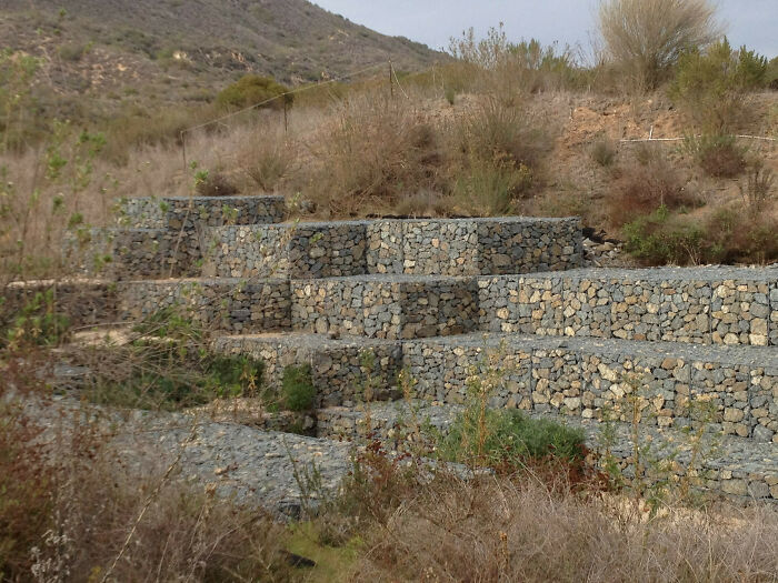 Stacked stone terraces resembling video game landscapes in a hilly, natural environment.