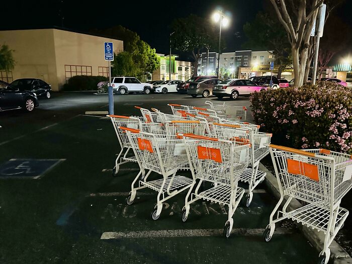 Shopping carts clutter handicap parking spot at night, showcasing lazy behavior.