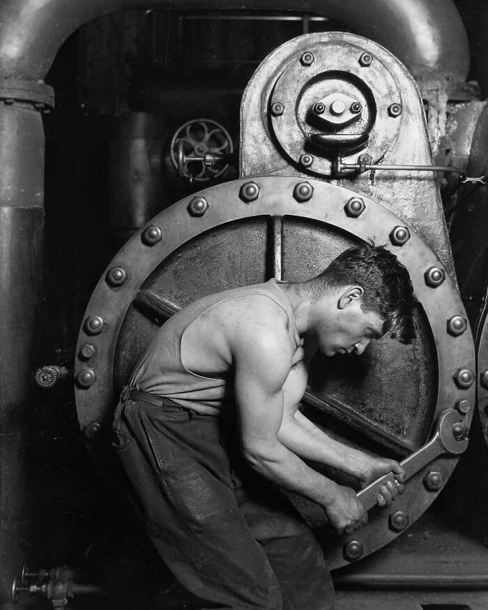 Worker using a large wrench on industrial machinery, illustrating learning from past industrial practices to shape the future.