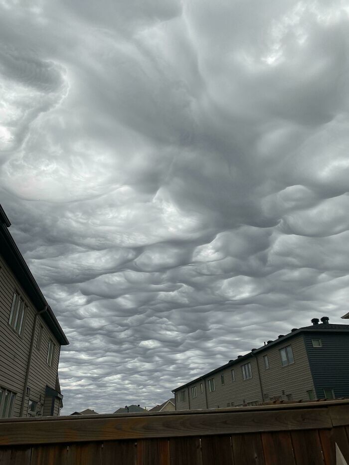 Cloudy sky above houses resembles a surreal, bad render, with textured clouds creating an uncanny visual effect.