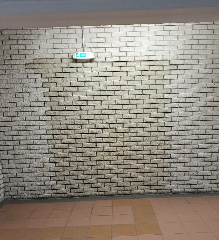 Brick wall with exit sign resembling a scene from a videogame.