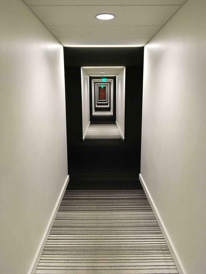 A long hallway with striped carpet and a geometric design resembling a scene from a videogame.