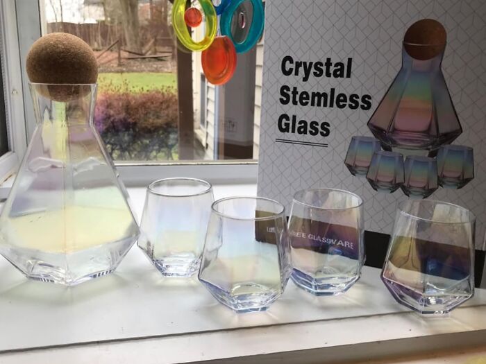 Crystal stemless glassware set displayed by a window.