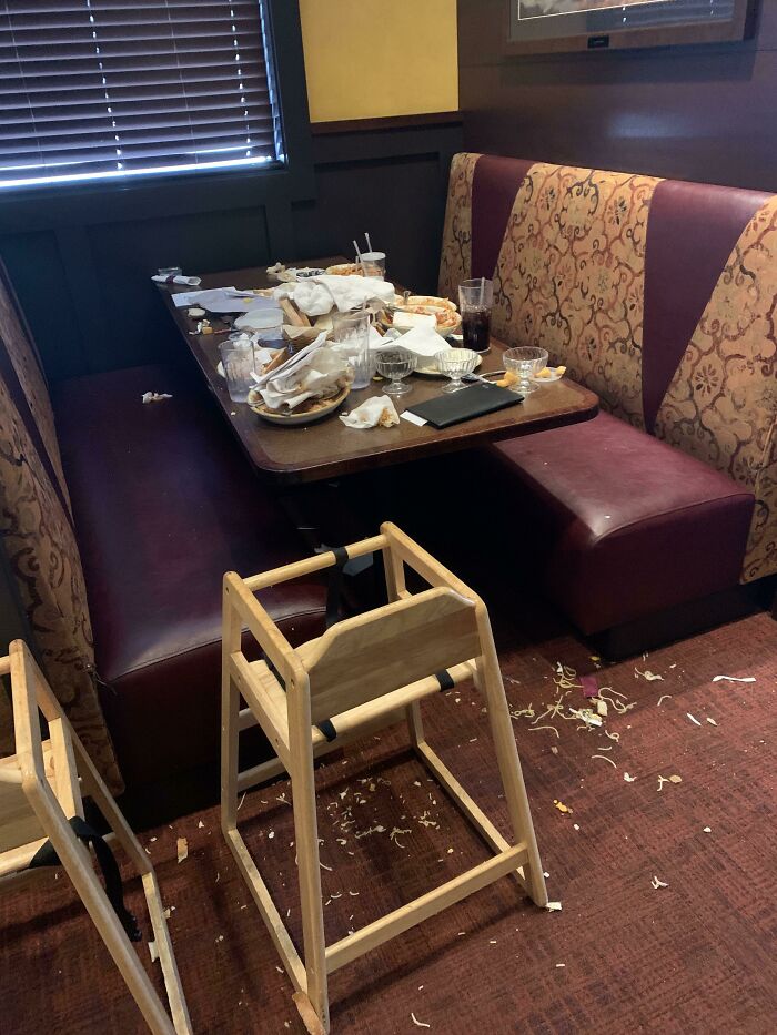 Messy restaurant booth with leftover food and chairs, illustrating lazy, infuriating behavior.