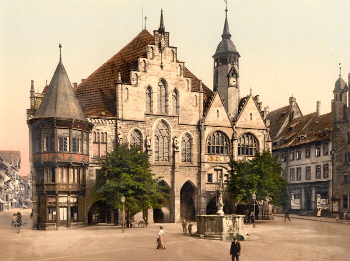 Historic color photo of medieval European building and town square from 100 years ago.