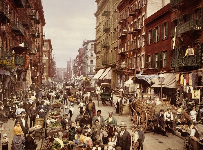 Historic color photo of a bustling city street 100 years ago, showcasing early 20th-century life and architecture.