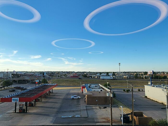 Gas station with circular clouds above, resembling videogame graphics with surreal sky effects.