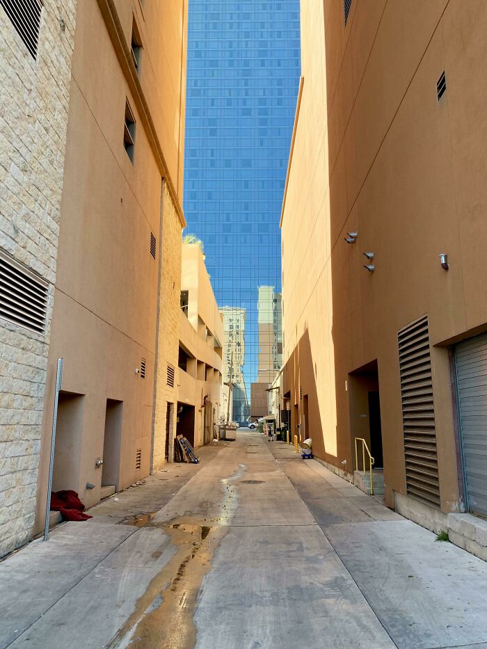 An alleyway framed by buildings with a reflection that makes it appear like a bad render.