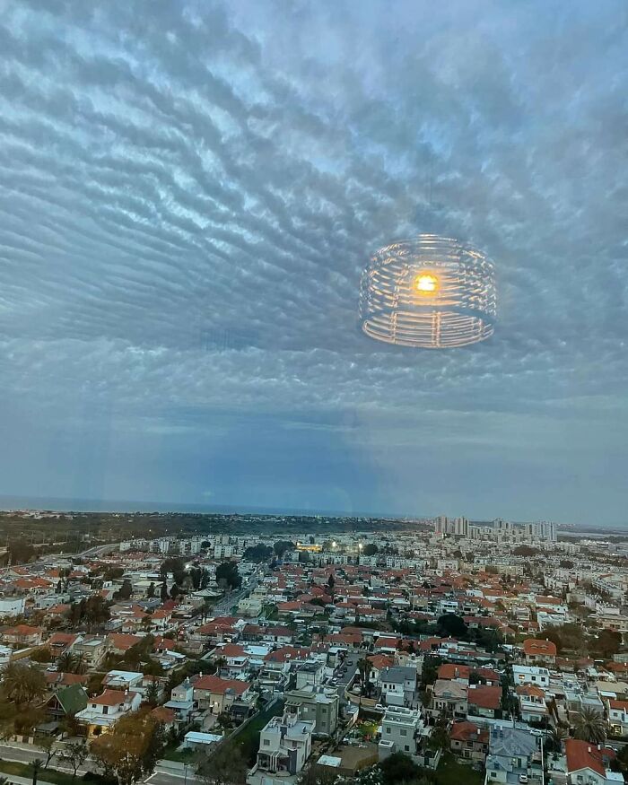 Cloudy sky over cityscape with a light reflection, resembling a bad render.