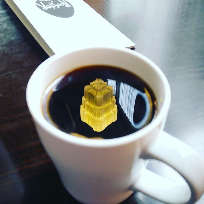 Coffee cup reflecting a structure resembling a videogame scene, with a menu on the table.